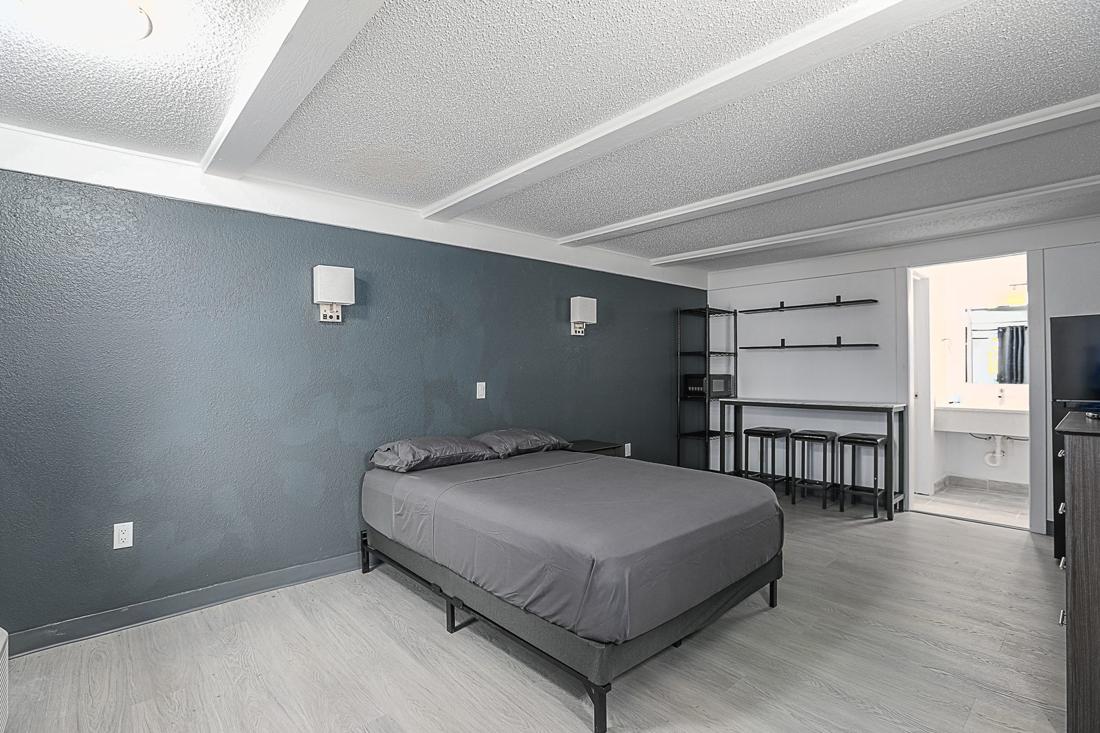 Studio with queen bed, kitchenette and bathroom door