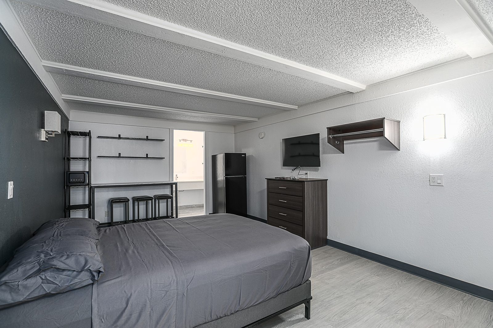 Studio with bed, dresser, TV and refrigerator